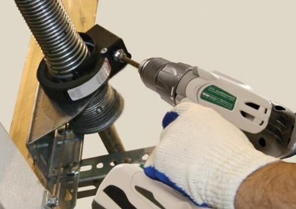a professional technician repairing a garage door spring at a residential property, highlighting the detailed process of garage door spring repair to ensure smooth and safe operation for Whitehall residents.